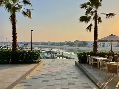 a patio with tables and chairs and palm trees and a marina at Studio *stunning SEA VIEW* in Dubai