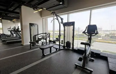 a gym with several treadmills and a large window at Homesgetaway Luxury 2BR at Socio Dubai hills in Dubai