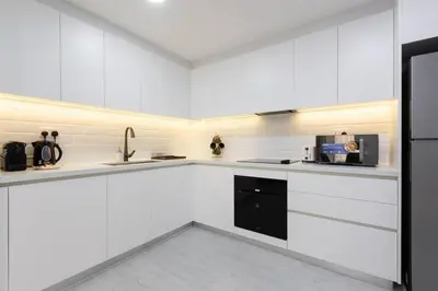 a white kitchen with white cabinets and a microwave at Stylish 3bdr apartment in Rimal 2 JBR in Dubai