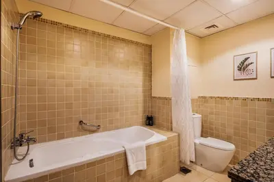 a bathroom with a tub and a toilet at Spacious, Deluxe, 5BR plus maidroom on JBR walk Next to Beach ,Tram & Mall by La Buena Vida Holiday Homes in Dubai