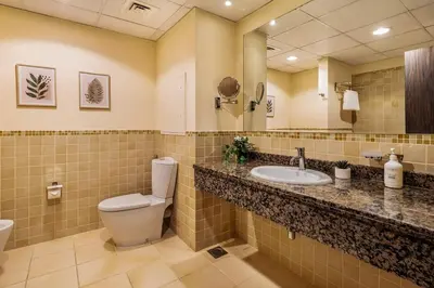 a bathroom with a toilet and a sink and a mirror at Spacious, Deluxe, 5BR plus maidroom on JBR walk Next to Beach ,Tram & Mall by La Buena Vida Holiday Homes in Dubai
