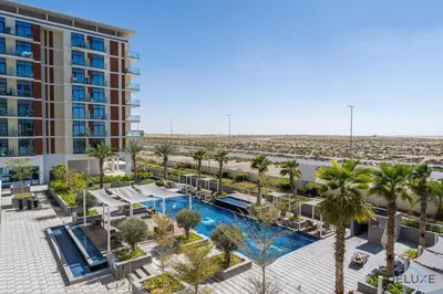 an aerial view of a resort with a pool and palm trees at Gorgeous Studio Apartment in DAMAC Celestia B Dubai South by Deluxe Holiday Homes in Dubai