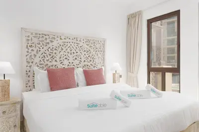 a white bedroom with two beds with price signs on them at Green living chic 1 bedroom apartment in Dubai