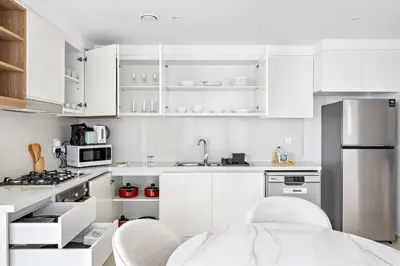 a white kitchen with white appliances and white cabinets at Silkhaus Elite 2BDR with View with Pool & Gym in Dubai