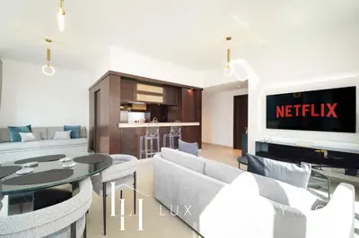 a living room with a tv and a table and chairs at LUX The Stunning Fountain View Suite in Dubai
