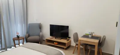 a room with a bed and a tv and a table at Shaista Azizi Residence - Al Furjan by Golden Casa in Dubai