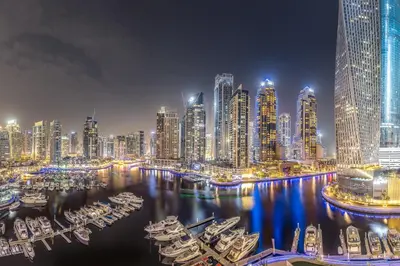 a city skyline at night with boats in the water at Panoramic canal views from brand new 3BD apartment in Dubai