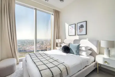 a white bedroom with a bed with a large window at GuestReady - Glamourous home in Downtown Dubai in Dubai