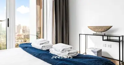 a pile of towels on a bed in front of a window at Upgraded 1BR Apartment in Bloom Tower B - JVC in Dubai