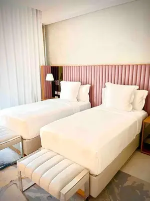 a hotel room with two beds and a bench at Best View Security System Burj Kalifa View in Dubai