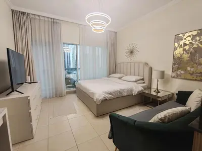 a bedroom with a bed and a tv and a couch at Downtown Dubai Mall walk & Burj Khalifa DIFC 5 mins in Dubai