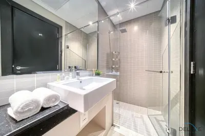 a white bathroom with a sink and a shower at Beautiful 2BR at Silverene Towers A Dubai Marina by Deluxe Holiday Homes in Dubai