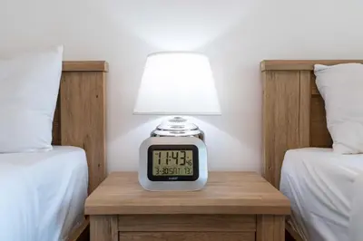 a clock sitting on a table next to two beds at Lux BnB I Una Tower I Lakes View in Dubai