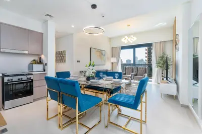 a kitchen and dining room with a table and blue chairs at Mystic - Act One Tower in Dubai
