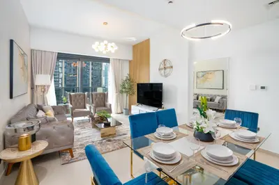 a living room with a table and blue chairs at Mystic - Act One Tower in Dubai