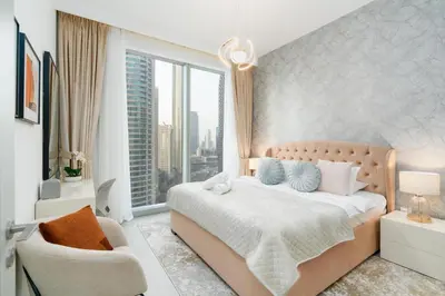 a bedroom with a bed and a chair and a window at Mystic - Forte Tower 2 in Dubai