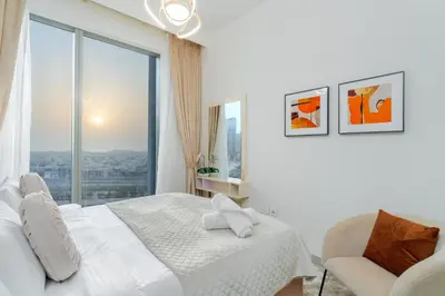 a white bedroom with a bed and a chair at Mystic - Forte Tower 2 in Dubai