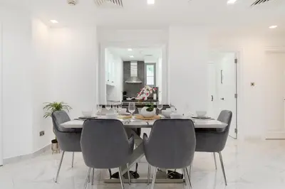a white dining room with a table and chairs at Mystic - Fully Renovated Spacious 2BR Apt. with Burj Views in Dubai