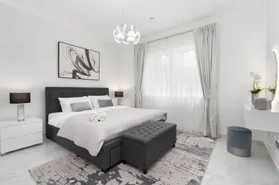 a white bedroom with a large bed and a chandelier at Mystic - Fully Renovated Spacious 2BR Apt. with Burj Views in Dubai