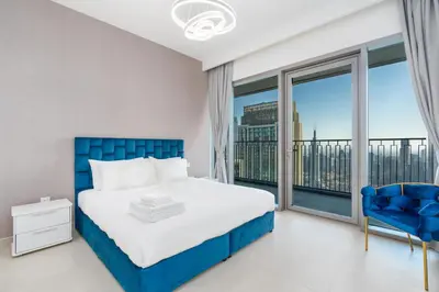 a bedroom with a blue bed and a large window at Burj Khalifa & Dubai Dancing Fountain View, 54th Floor & Dubai Mall Access in Dubai