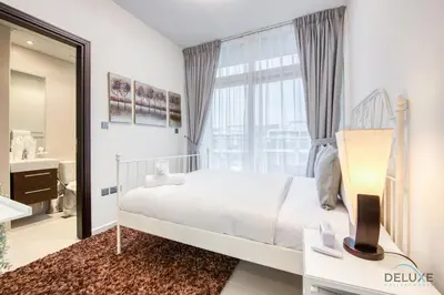 a bedroom with a bed and a large window at Tranquil 3BR Townhouse at Albizia Damac Hills 2 by Deluxe Holiday Homes in Dubai