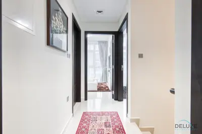 a hallway with white walls and a red rug at Tranquil 3BR Townhouse at Albizia Damac Hills 2 by Deluxe Holiday Homes in Dubai
