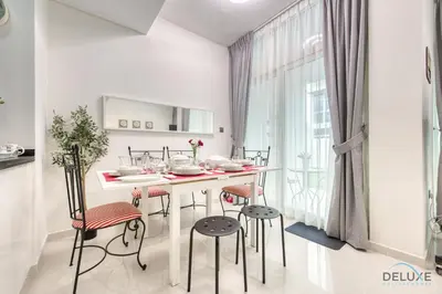 a white kitchen with a table and stools at Tranquil 3BR Townhouse at Albizia Damac Hills 2 by Deluxe Holiday Homes in Dubai
