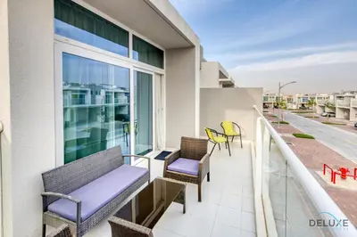a balcony with benches and chairs on a building at Tranquil 3BR Townhouse at Albizia Damac Hills 2 by Deluxe Holiday Homes in Dubai
