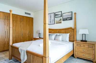 a bedroom with a large bed and wooden cabinets at Sophisticated 3BR w/ Assistant’s Room at Al Fattan Marine Towers 2 JBR by Deluxe Holiday Homes in Dubai
