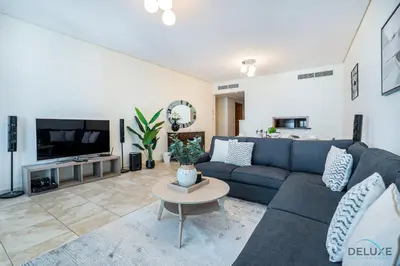 a living room with a blue couch and a tv at Sophisticated 3BR w/ Assistant’s Room at Al Fattan Marine Towers 2 JBR by Deluxe Holiday Homes in Dubai
