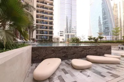 two white stools sitting on a patio with tall buildings at Pool View One Bed Room Business Bay in Dubai