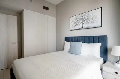 a bedroom with a white bed with a blue headboard at Pool View One Bed Room Business Bay in Dubai