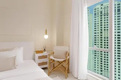 a bedroom with a bed and a desk and a window at Maison Privee - Modern Beach Living in the Heart of Dubai Marina in Dubai