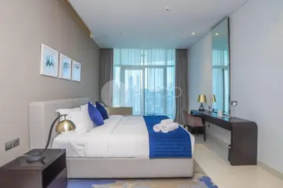 a bedroom with a bed with a desk and a bed sidx sidx sidx at Stunning 1 BR Damac Maison Prive in Dubai