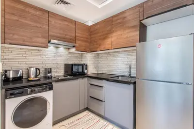 a kitchen with stainless steel appliances and wooden cabinets at Holiday Studio In JVC 0107, Dubai in Dubai