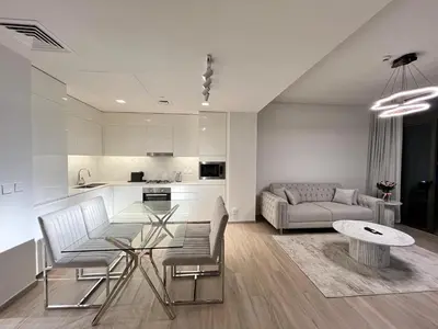 a kitchen and a living room with a table and chairs at Palace Dubai Creek Harbour Residences Skyline Apartment in Dubai