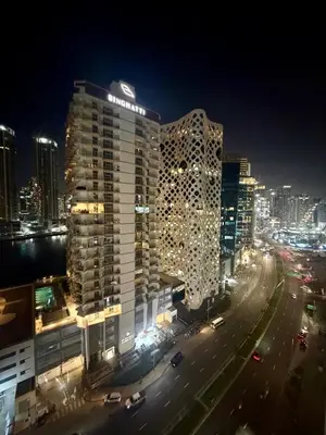 a large building in a city at night at Cozy Spacious AG Tower Business Bay, Dubai in Dubai