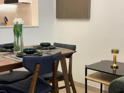 a dining room table with two chairs and a table with plates and flowers at ASHRI HH, Luxurious Apt in JVC in Dubai