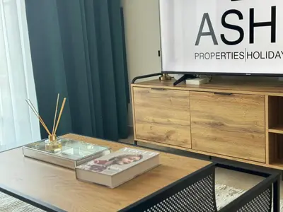 a table with a tv on top of a dresser at ASHRI HH, Luxurious Apt in JVC in Dubai