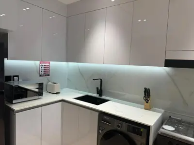a white kitchen with a sink and a microwave at ASHRI HH, Luxurious Apt in JVC in Dubai