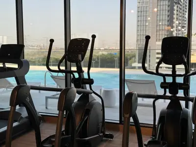 a gym with cardio equipment in front of a window at ASHRI HH, Luxurious Apt in JVC in Dubai