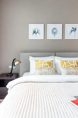 a bedroom with a white bed with four pictures on the wall at The Smart Concierge - Damac Maison Prive in Dubai