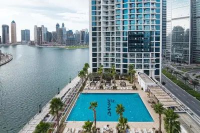 an aerial view of a swimming pool in front of a large building at The Smart Concierge - Damac Maison Prive in Dubai