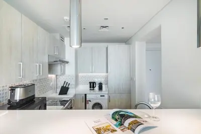 a kitchen with white cabinets and a table with a wine glass at The Smart Concierge - Seven Palm in Dubai