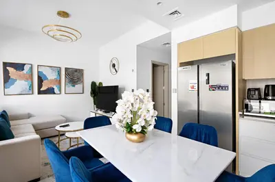 a kitchen and living room with a white table and blue chairs at Luxurious 6-Sleeper Villa with Large Outdoor Patio in Dubai