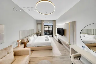 a bedroom with a bed and a couch and a mirror at Belgravia Square, Jumeirah Village Circle in Dubai