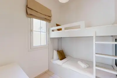 a bedroom with white bunk beds and a window at The Springs - Tranquil Two Bedroom Villa in Dubai