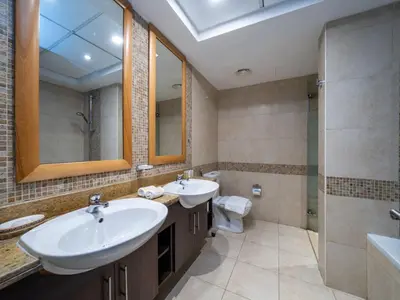 a bathroom with two sinks and a shower and a toilet at 2 Bedroom Delight in The Greens Dubai in Dubai