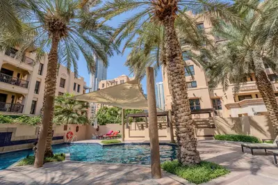a courtyard with palm trees and a swimming pool at GuestReady - Groove Getaway in Downtown Dubai in Dubai