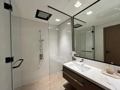 a bathroom with a shower and a sink and a mirror at Palace Dubai Creek Harbour Residences Skyline Apartment in Dubai
